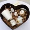 Presentación completa de box desayuno con forma de corazón, vajilla de cerámica y frascos de vidrio sobre viruta de madera.