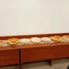 Plato con sándwiches de miga y chips salados junto a canastas de mimbre con sobres de té y café para catering empresarial.