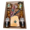 Contenido de box cervecero gourmet con cervezas Corona, queso holanda, salamín al vacío y frascos de snacks.