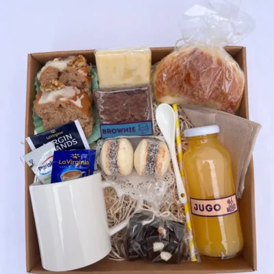 Box desayuno gourmet de regalo con taza blanca de cerámica, frascos de cookies y frutos secos, alfajores de maicena, brownie y café.
