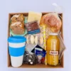 Box desayuno gourmet de regalo con vaso térmico de acero blanco, frascos de cookies y frutos secos, alfajores de maicena y pastelería.