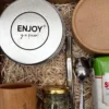 Plano angular de box matero de Enjoy con mate de madera, bombilla, cuchara grabada, frasco de burrito y variedad de dulces.