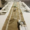Vajilla de cristal y tazas de vidrio exhibidas sobre mantel de arpillera para evento de Enjoy.