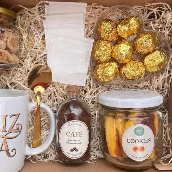 box-desayuno-dia-de-la-madre-detalle-dulzuras-cafe Detalle interior del box con botella de café molido, frasco de amarettis, frasco de cookies y bombones dorados en estuche de corazón.