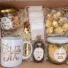 box-desayuno-dia-de-la-madre-detalle-dulzuras-cafe-dulces-taza-cuchara-filtros Detalle del box con taza, cucharita dorada, sobres filtro y dulzuras del Día de la Madre.